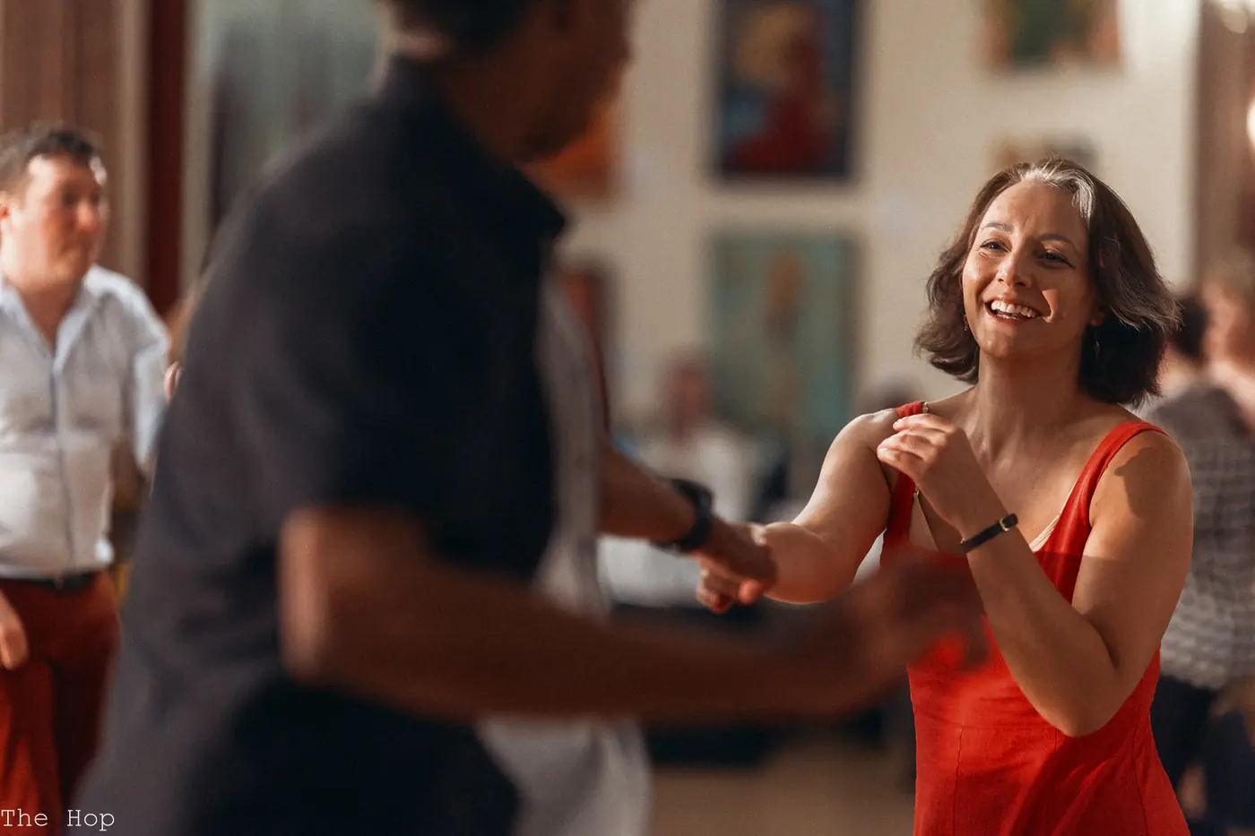 A dancer in a red dress laughing with her partner